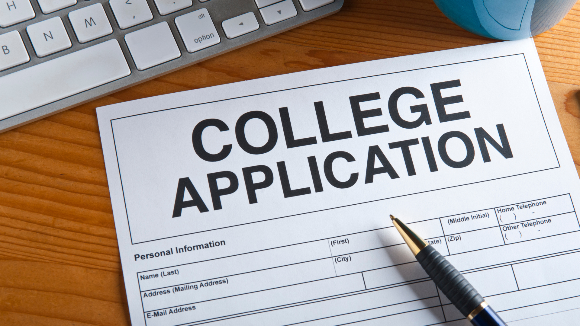 Image depicts a piece of paper with "COLLEGE APPLICATION" written at the top. There a several fields under it, such as name, address, email. A pen lays on top of the paper